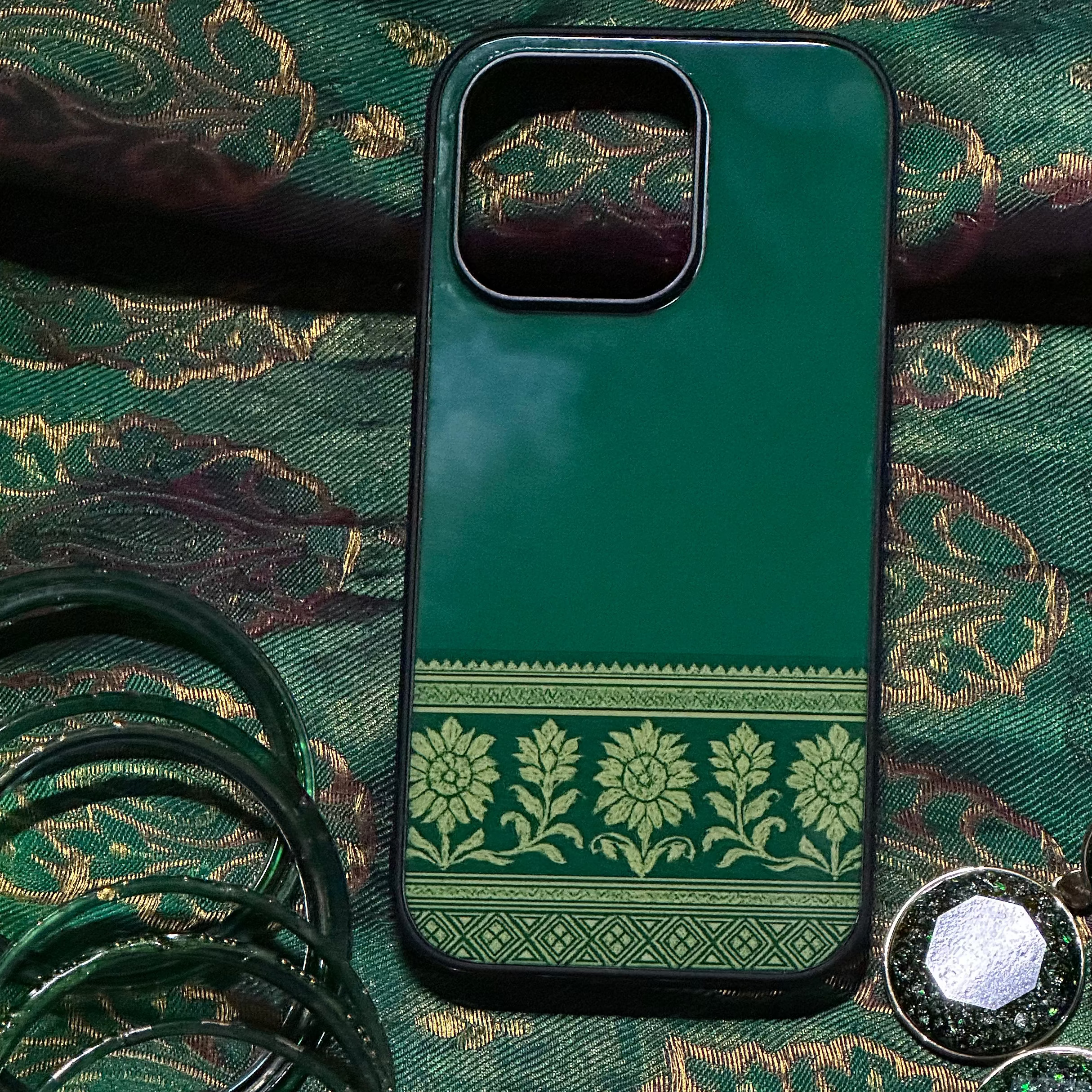 Green phone case with decorative pattern on a green fabric background